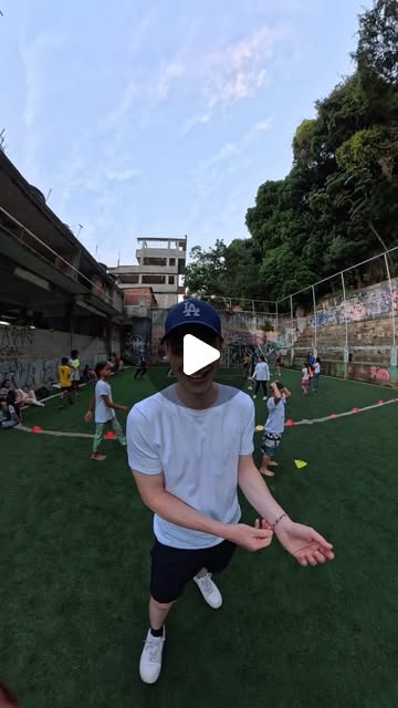 Luca, a volunteer from Canada, on the pitch in Vidigal with children playing behind him.