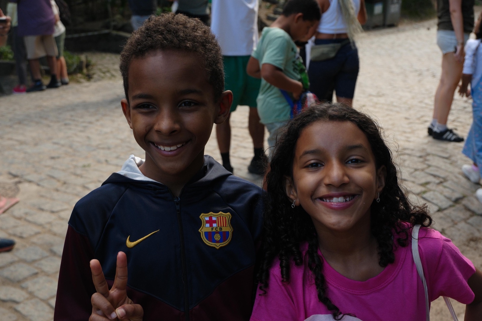 A boy in a football shirt and a girl smile side by side in Vidigal.