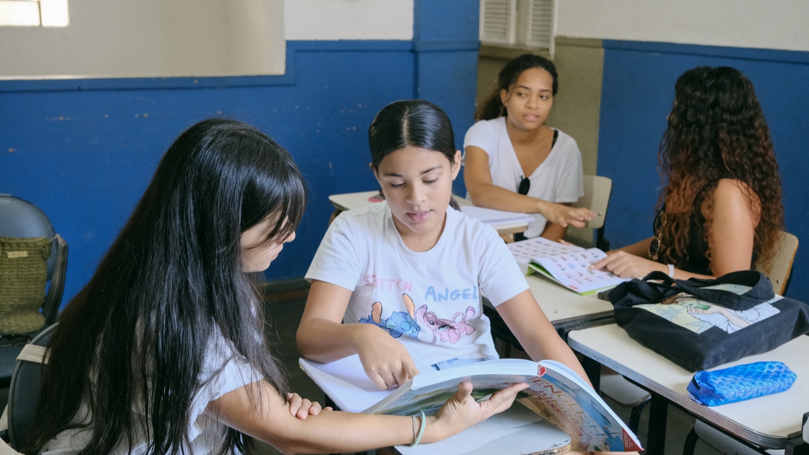 Students and young people read through materials together at desks.