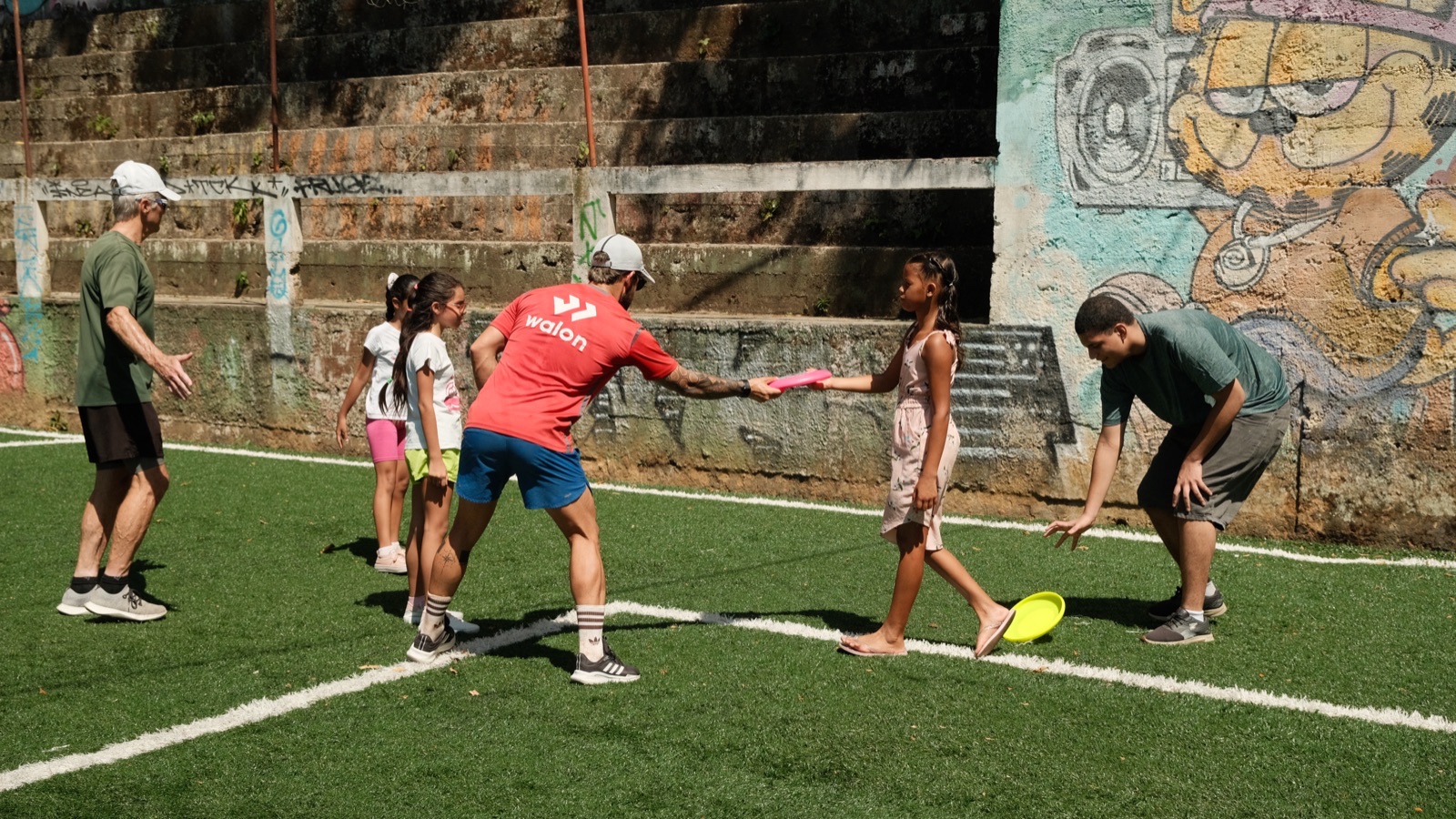 Children and volunteers play a game on the artificial pitch below the graffiti wall.